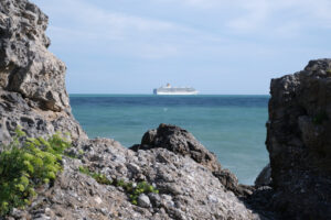 Sea cliff with waves and cruise ship. The waves of the Ligurian sea crash on the rocks. - MyVideoimage.com | Foto stock & Video footage