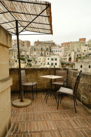 Sedia con tavolo in cortile. Chair with iron table in a courtyard in the city of Matera. Beige stone wall with marble air grilles. - MyVideoimage.com | Foto stock & Video footage