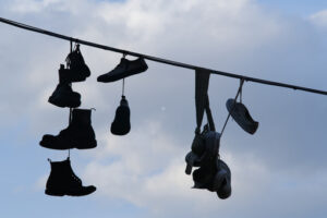 Shoes hanging. Row of shoes hanging from an electric cable against the backdrop of sky with sunshine. - MyVideoimage.com | Foto stock & Video footage