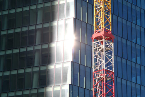 Skyscraper construction in Milan. Construction site tower crane for the construction of the PWC Libeskind skyscraper in Milan. Glass facade with sun reflection. - MyVideoimage.com | Foto stock & Video footage