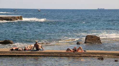 Some people sunbathe out on the pier in the sea of Livorno. Pano - MyVideoimage.com