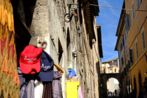 Souvenir shop with hats hanging on the door in the ancient city of Assisi. - MyVideoimage.com