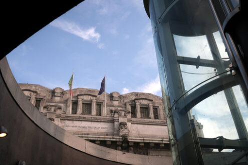 Stazione di Milano. Panoramic lift with glass facade. In the background the central station of Milan in imperial neoclassical style. - MyVideoimage.com | Foto stock & Video footage