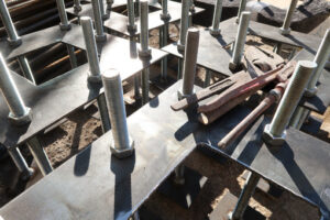 Steel plates, construction site. Construction site for a building with a steel structure. Plates with anchor bolts for mounting steel columns on a reinforced concrete foundation. - MyVideoimage.com | Foto stock & Video footage