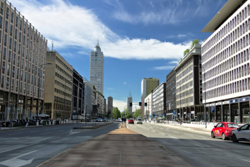 Strada di Milano. Edifici, strade e traffico a Milano. Auto rossa, traffico. Cielo azzurro con nuvole. - MyVideoimage.com | Foto stock & Video footage