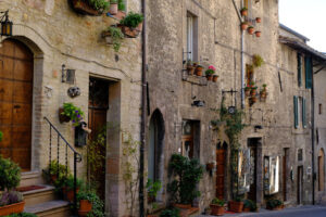 Street of the city of Assisi with typical old stone and brick houses. Facades, doors and windows are decorated with flower pot plants - MyVideoimage.com