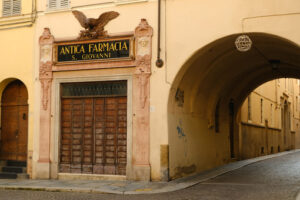 Street with arch and pharmacy shop with ancient sign with eagle. - MyVideoimage.com