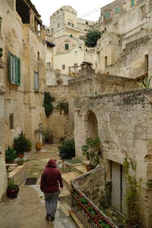 Street with courtyard in Matera. Courtyard in a street of the ancient city of Matera. A person walks down the street. Houses in tufa stone. - MyVideoimage.com | Foto stock & Video footage