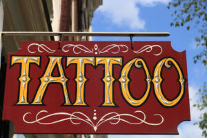 Tattoo shop sign. Red panel with blue sky. - MyVideoimage.com