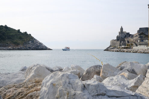 Tourists in Portovenere. Church of San Pietro in Portovenere overlooking the sea. Boats with tourists visiting the Cinque Terre. - MyVideoimage.com | Foto stock & Video footage