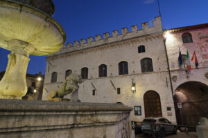 Town square of Assisi with the Palazzo dei Priori and fountain at night. The city of San Francesco with the lights of the night. - MyVideoimage.com