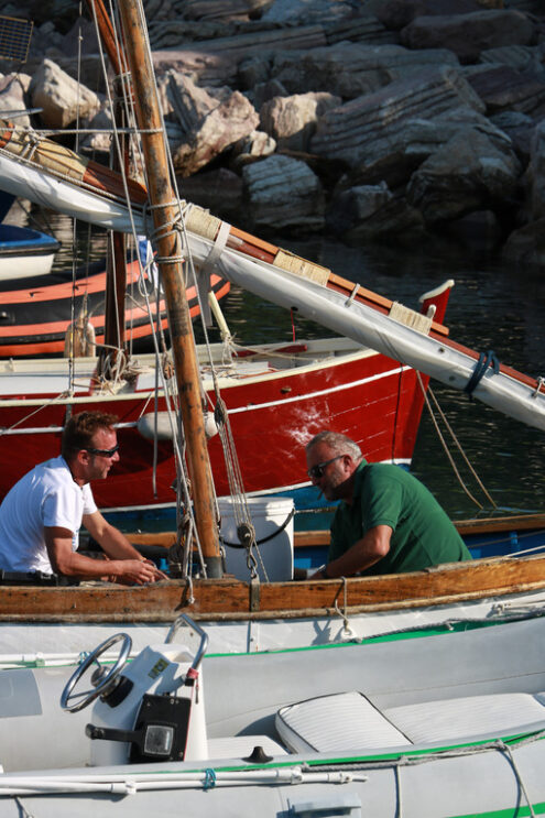 Trip to the sea. Colorful fishing boats moored at the harbor. Two fishermen are preparing to set sail. Sea pictures. - MyVideoimage.com | Foto stock & Video footage