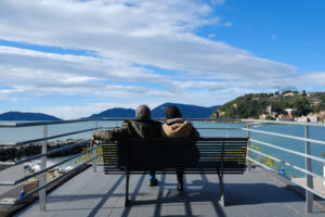 Two people sitting on a bench on a terrace overlooking the Lerici sea in Liguria. - MyVideoimage.com | Foto stock & Video footage