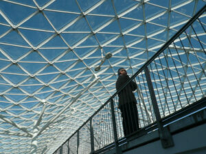 Uomo d’affari. Businessman waiting inside a pavilion of the Milan fair. Modern architecture with steel and glass lattice structure. Milano foto - MyVideoimage.com | Foto stock & Video footage