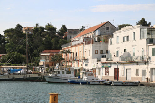 Village of  Ischia Porto with its typical Mediterranean houses. In the foreground the sea with some boats. - MyVideoimage.com