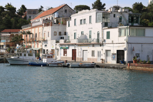 Village of  Ischia Porto with its typical Mediterranean houses. In the foreground the sea with some boats. - MyVideoimage.com