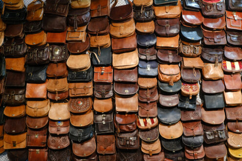 Wall display of leather bags at the craft fair. Leather bags in various colors, from brown to black. - MyVideoimage.com