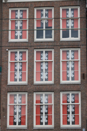 Windows with curtains in the colors of the Amsterdam flag. Red and black flag with the Saint Andrew crosses. - MyVideoimage.com