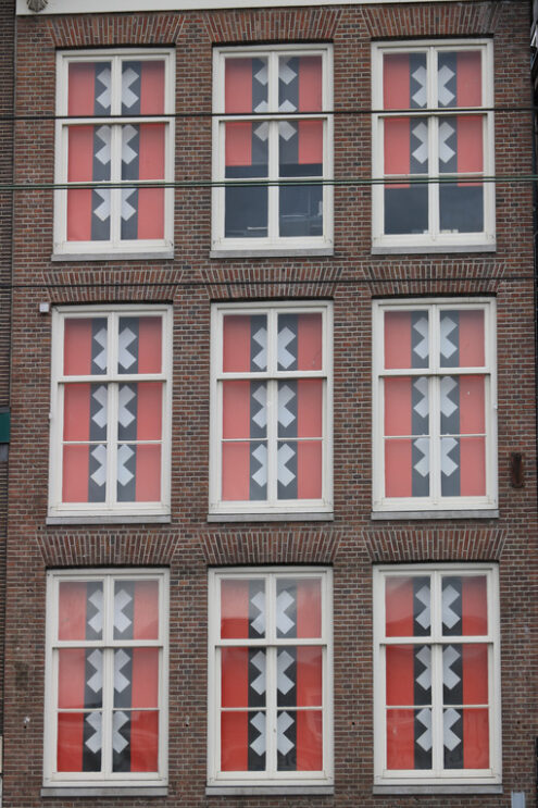 Windows with curtains in the colors of the Amsterdam flag. Red and black flag with the Saint Andrew crosses. - MyVideoimage.com