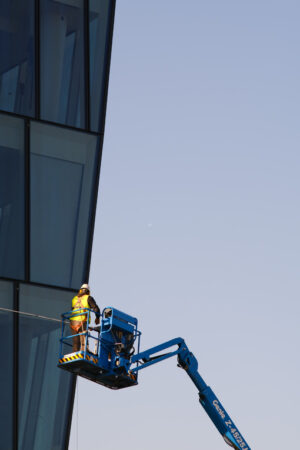 Worker on an elevator basket cleans the facade of a glass-clad building. - MyVideoimage.com | Foto stock & Video footage