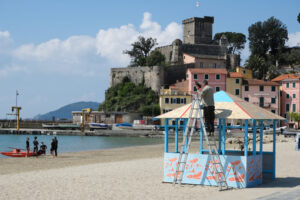 Worker performs maintenance work on a seaside gazebo next to a red skate. - MyVideoimage.com | Foto stock & Video footage