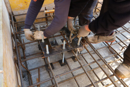 Workers mount steel plates Workers mount steel plates with anchor bolts for columns on a reinforced concrete foundation. - MyVideoimage.com | Foto stock & Video footage